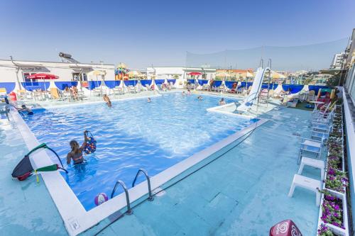 a large swimming pool with people in the water at Hotel Stella Maris in Cesenatico