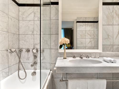 ein Bad mit einer Badewanne, einem Waschbecken und einer Dusche in der Unterkunft Le Dokhan's Paris Arc de Triomphe, a Tribute Portfolio Hotel in Paris