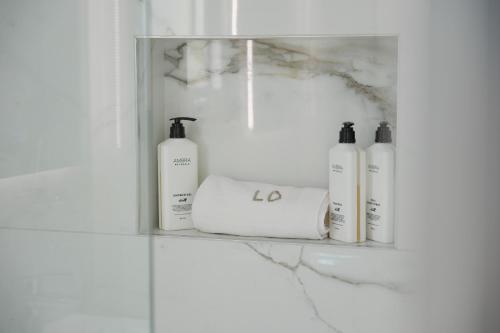 a shelf with four bottles of soap and towels at Loutsiana Deluxe Apts in Ayia Napa