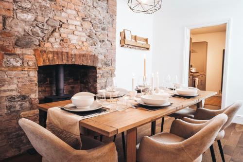 a dining room with a wooden table and a fireplace at Pye Corner Cottage, by Solace Stays in Bellaghy