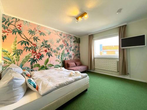 a bedroom with a bed and a flowery wall at WannerHus Hotel in Grömitz