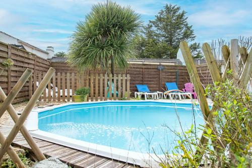 - une piscine dans une cour avec des chaises et un palmier dans l'établissement New - Gite Angelina piscine et spa, à Saint-Jean-de-Monts