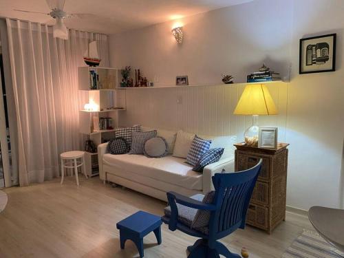 een woonkamer met een witte bank en blauwe stoelen bij Flat aconchegante à beira-mar in Vera Cruz de Itaparica