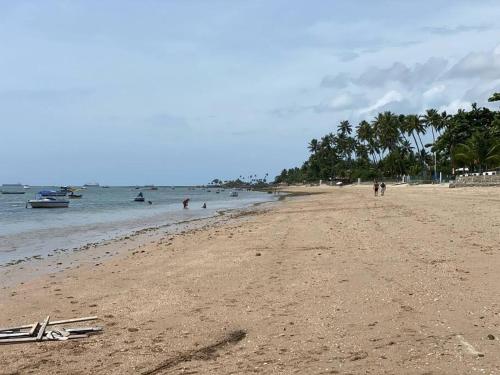 a sandy beach with people swimming in the ocean at Flat aconchegante à beira-mar in Vera Cruz de Itaparica