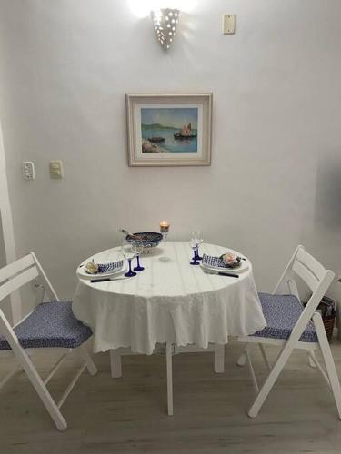 a table with two chairs and a white table and a painting at Flat aconchegante à beira-mar in Vera Cruz de Itaparica