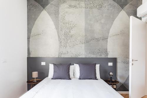 Un dormitorio con una cama blanca y una pared con arcos. en Residence Moretti Piano Terra en Udine