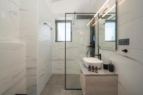 een witte badkamer met een wastafel en een douche bij Sun Flower Villas in Agia Marina Nea Kydonias