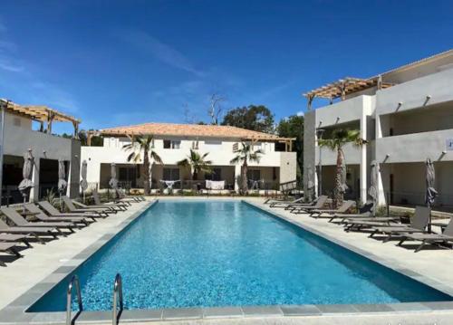 une piscine avec des chaises et un bâtiment en face d'un hôtel dans l'établissement Bravone 74- piscine en résidence-clim-wifi-pieds dans l'eau, à Linguizzetta