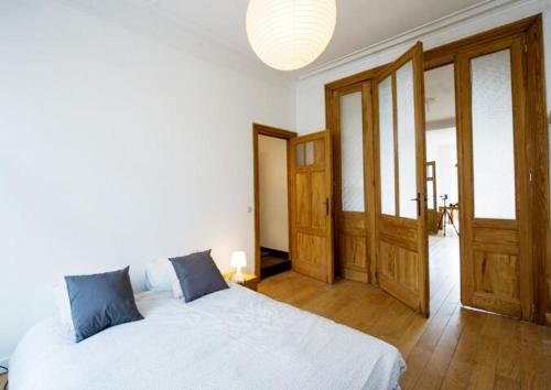 1 dormitorio con cama blanca y puertas de madera en Grand appartement d'artiste cosy et proche de tout, en Bruselas