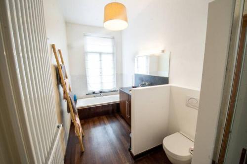 La salle de bains est pourvue de toilettes, d'un lavabo et d'une baignoire. dans l'établissement Grand appartement d'artiste cosy et proche de tout, à Bruxelles