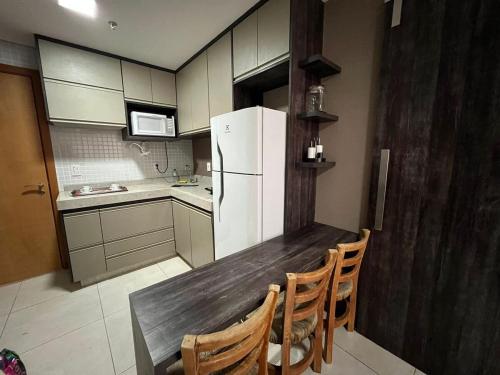 Il comprend une cuisine équipée d'une table en bois et d'un réfrigérateur. dans l'établissement Econo Brookfield Towers - Jardim Goias, à Goiânia