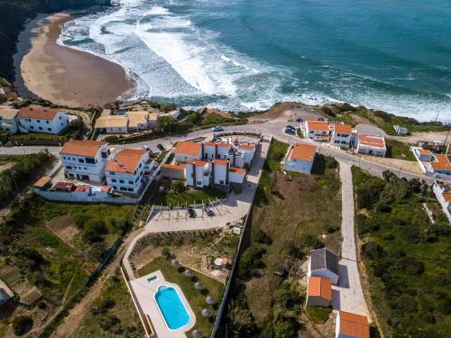an aerial view of a beach with houses and the ocean at Falésias da Arrifana in Praia da Arrifana
