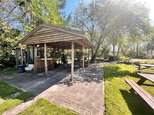 un pabellón en un parque con mesas de picnic y bancos en Camping de Beerte, en Beerta