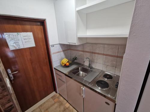 a small kitchen with a sink and a wooden door at VILLA ŠIMOVIĆ APARTMENTS in Baška Voda