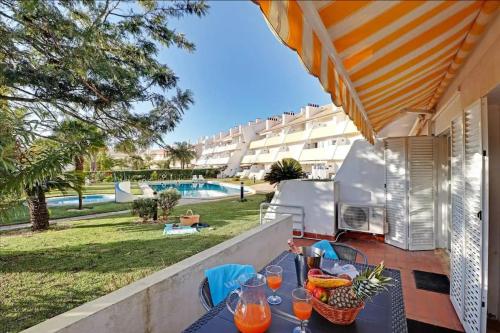 a table with drinks on a balcony with a view of a pool at Falésia Sunny Apartment in Quarteira