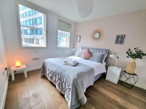 a bedroom with a bed and two windows at London City Apartments in London