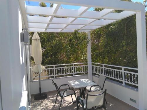 a white pergola on a balcony with a table and chairs at Hotel Sunshine Matala in Matala