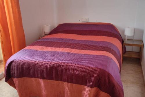 1 cama con colcha a rayas de colores en una habitación en adosado con piscina en Cabo de Gata 4p, en Cabo de Gata