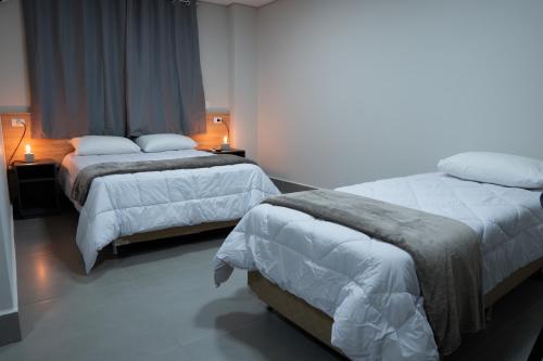 two beds in a hotel room with two lamps at DICOPI HOTEL in Maringá