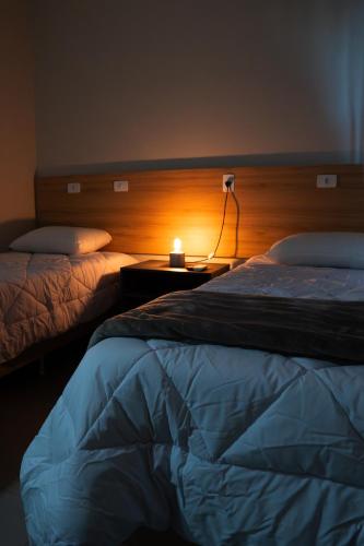 a bedroom with two beds and a lamp on a table at DICOPI HOTEL in Maringá