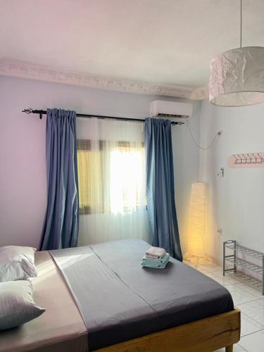 Schlafzimmer mit einem großen Bett und blauen Vorhängen in der Unterkunft Los Angeles to Conakry *KIPE* in Conakry