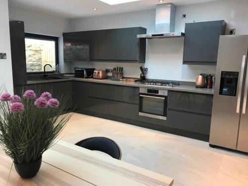 a kitchen with black and white appliances and a vase with purple flowers at ※ Lovely Central Bath House- with Parking ※ in Bath