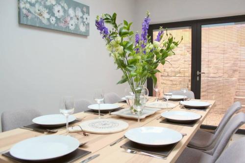 a wooden table with chairs and a vase of flowers at ※ Lovely Central Bath House- with Parking ※ in Bath