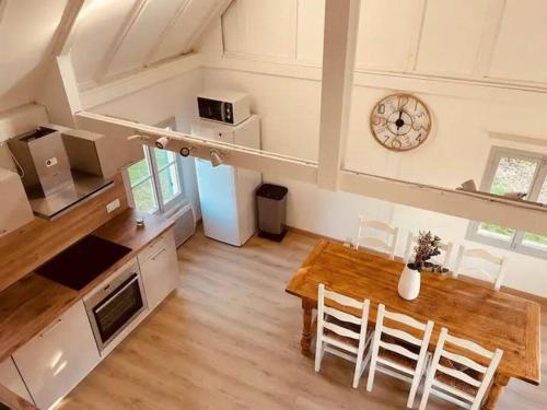 cocina y comedor con mesa y reloj en Beach House by Melrose, en Asnelles