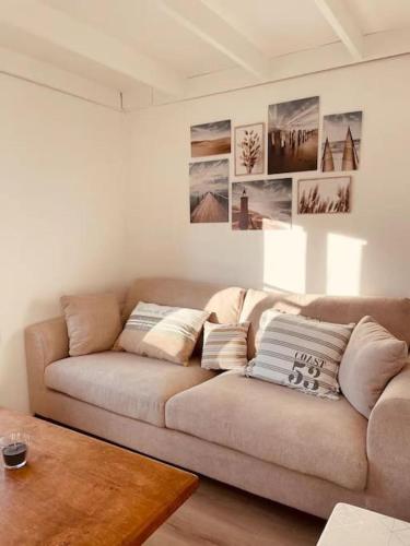 - un canapé dans le salon avec des photos sur le mur dans l'établissement Beach House by Melrose, à Asnelles
