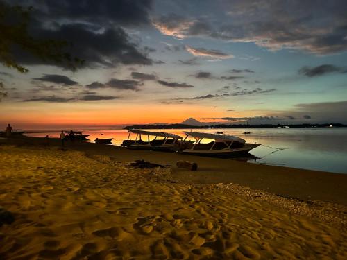 una barca seduta sulla spiaggia al tramonto di Sunny Rose Bungalows Gili Air a Gili Air