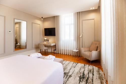 a hotel room with a white bed and a chair at Avenida Boutique Hotel in Viseu
