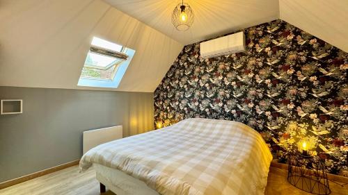 Un dormitorio con una pared de acento floral y una cama en Cottage les Pins, en Stella-Plage