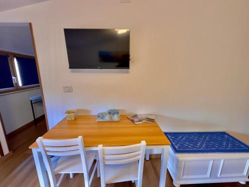a dining room table with white chairs and a television at Casa del Mare in Bosa