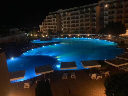 ein großer blauer Pool in der Nacht mit Gebäuden in der Unterkunft Midia SP Apartments in Aheloy