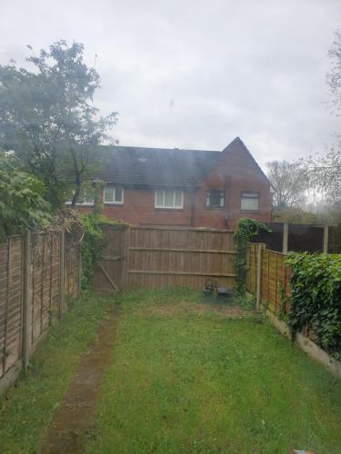 a house with a wooden fence in front of a yard at Greys room share in Warrington