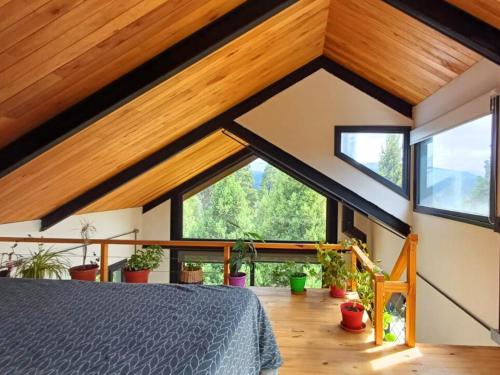 um quarto com tectos em madeira e janelas grandes em Casa de montaña La Cumba Patagonia. em San Martín de los Andes