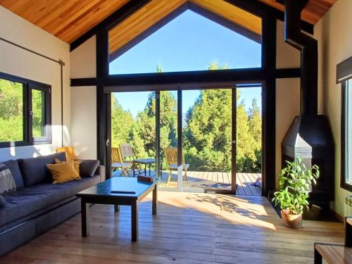 un salon avec un canapé et une cheminée dans l'établissement Casa de montaña La Cumba Patagonia., à San Martín de los Andes