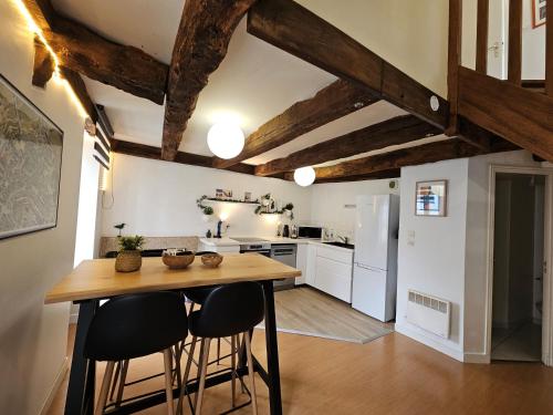 - une cuisine avec une table en bois et quelques tabourets dans l'établissement Duplex au coeur de Dinan, à Dinan