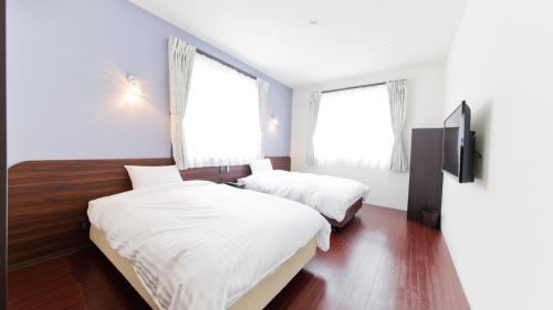 a bedroom with two beds and two windows at AIRAIKUHOTEL kagoshima in Aira