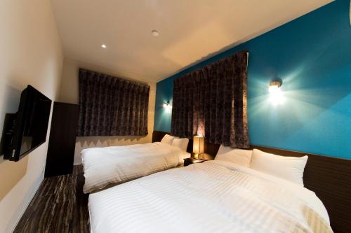 a bedroom with a white bed and a blue wall at AIRAIKUHOTEL kagoshima in Aira