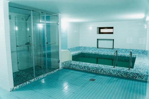 uma casa de banho com um chuveiro e uma cabina de duche em vidro. em Green Hill em Almaty