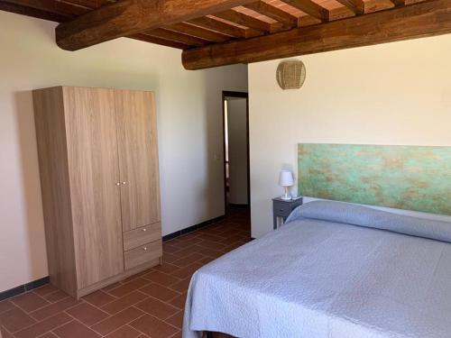a bedroom with a bed and a wooden cabinet at Agriturismo Diffuso Monte Oliveto Maggiore in Chiusure