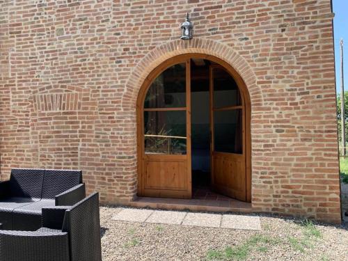 a brick building with a wooden door and a chair at Agriturismo Diffuso Monte Oliveto Maggiore in Chiusure