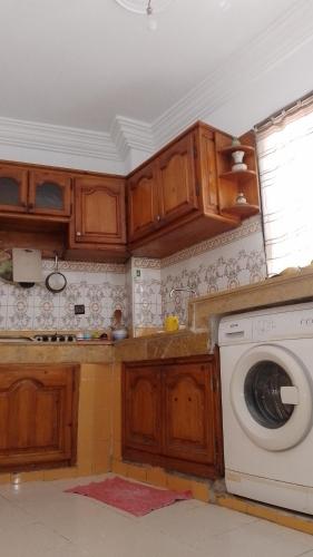 uma cozinha com armários de madeira e uma máquina de lavar roupa em Paradise house em Casablanca