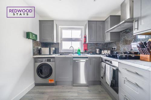 a kitchen with a sink and a washing machine at Centrally Located Serviced Apartments in Aldershot Town Centre, Free WiFi By Redwood Stays in Aldershot
