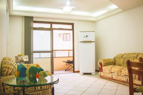 a living room with a couch and a table and a refrigerator at Apto Wifi, Elevador, Varanda e Garagem na praia de Guarapari in Guarapari