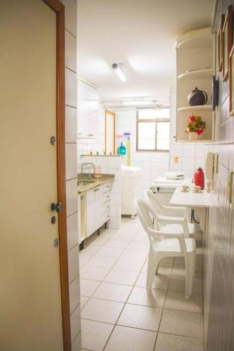 a kitchen with white cabinets and a table and chairs at 2 Quartos com Elevador, Varanda e Garagem na praia de Guarapari in Guarapari