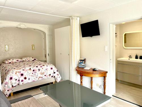 Schlafzimmer mit einem Bett, einem Tisch und einem Waschbecken in der Unterkunft Le Gîte du Sommerberg in Niedermorschwihr