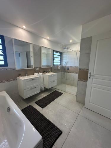a white bathroom with two sinks and a shower at Grande Villa Familiale avec piscine et Accès Privé à la Plage in Païta