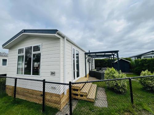 een klein wit tiny house met een veranda bij Beach Resort Kamperland - 264 in Kamperland